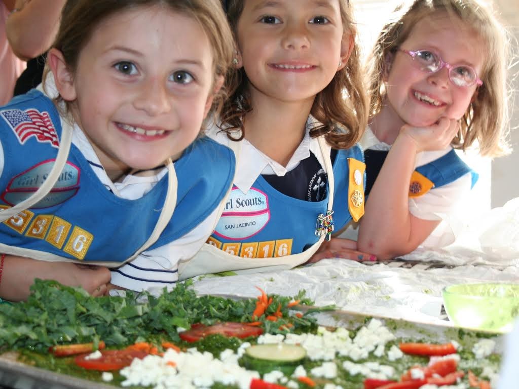 Girl scouts smile over plate of vegetables.