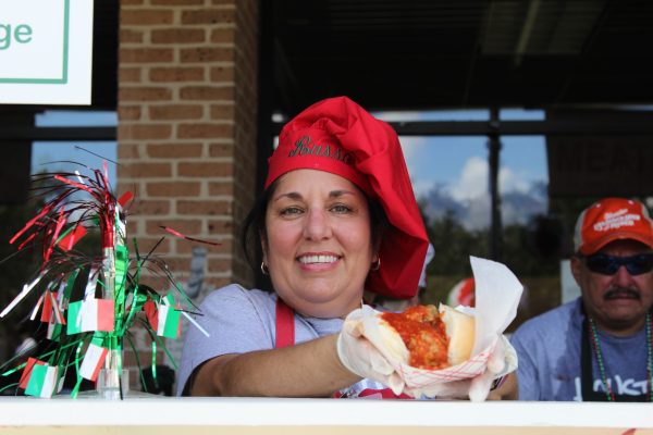 a chef in a red hat serves a meatball sub